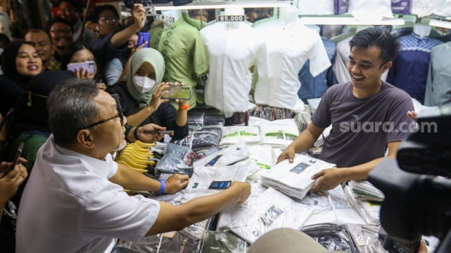 Menteri Perdagangan (Mendag) Zulkifli Hasan memilih pakaian saat melakukan kunjungan di Blok A Pasar Tanah Abang, Jakarta, Kamis (14/3/2024). [Suara.com/Alfian Winanto]