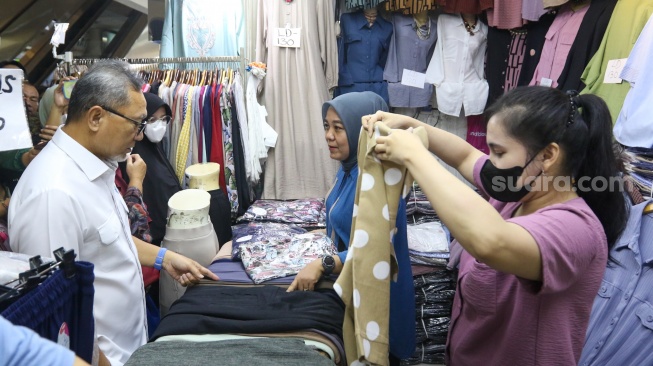 Menteri Perdagangan (Mendag) Zulkifli Hasan memilih pakaian saat melakukan kunjungan di Blok A Pasar Tanah Abang, Jakarta, Kamis (14/3/2024). [Suara.com/Alfian Winanto]