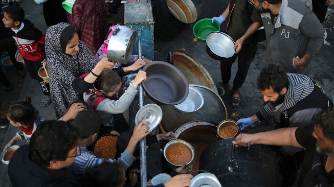 Pengungsi Palestina mengumpulkan makanan yang disumbangkan oleh sebuah badan amal untuk berbuka puasa di Rafah, Jalur Gaza Selatan, Senin (11/3/2024). [AFP]