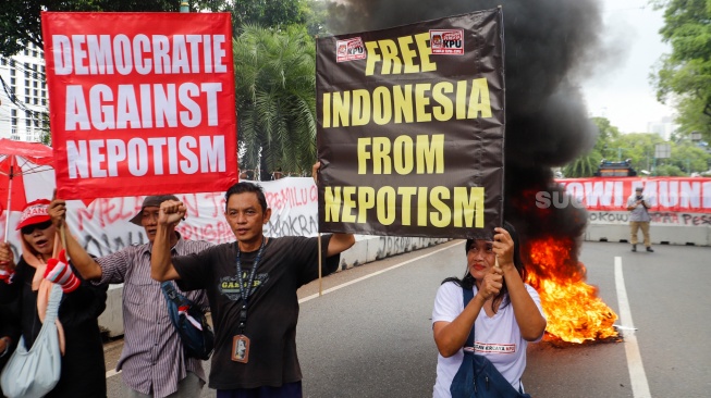 Massa yang tergabung dalam Gerakan Masyarakat Sipil Selamatkan Demokrasi Indonesia membakar ban saat menggelar aksi di depan Gedung Komisi Pemilihan Umum (KPU) RI, Jakarta,  Senin (18/3/2024). [Suara.com/Alfian Winanto]