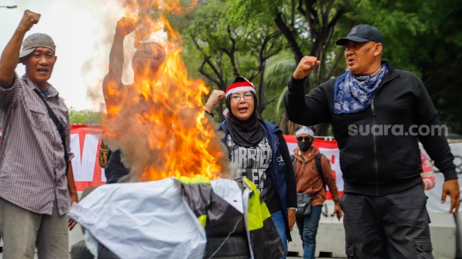 Massa yang tergabung dalam Gerakan Masyarakat Sipil Selamatkan Demokrasi Indonesia membakar ban saat menggelar aksi di depan Gedung Komisi Pemilihan Umum (KPU) RI, Jakarta,  Senin (18/3/2024). [Suara.com/Alfian Winanto]