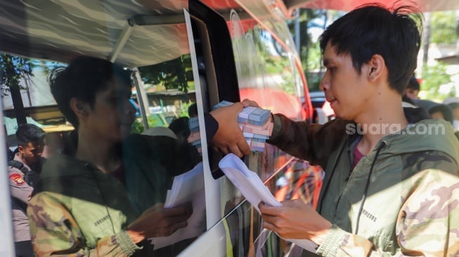 Warga antre untuk menukarkan uang baru di Pasar Tebet Barat, Jakarta, Selasa (19/3/2024). [Suara.com/Alfian Winanto]