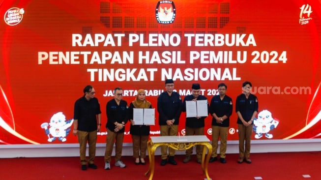 Ketua KPU Hasyim Asy'ari (tengah) bersama para anggota KPU menunjukkan Berita Acara Penetapan Hasil Pemilu 2024 yang sudah ditandatangani saat Rapat Pleno Terbuka Penetapan Hasil Pemilu 2024 Tingkat Nasional di Kantor KPU RI, Jakarta, Rabu (20/3/2024). [Suara.com/Alfian Winanto]