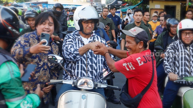 Capres nomor urut satu, Anies Baswedan menyalami warga saat mengendarai Vespa usai membeli Takjil untuk berbuka puasa di Pasar Takjil Benhil, Jakarta, Rabu (20/3/2024). [Suara.com/Alfian Winanto]