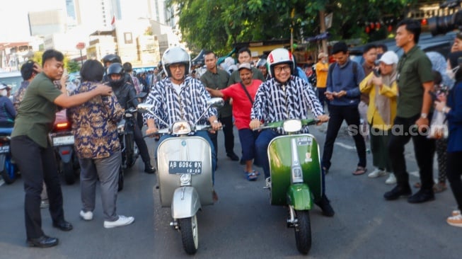 Pasangan Capres dan Cawapres nomor urut satu, Anies Baswedan (kiri) dan Muhaimin Iskandar (kanan) mengendarai Vespa usai membeli Takjil untuk berbuka puasa di Pasar Takjil Benhil, Jakarta, Rabu (20/3/2024). [Suara.com/Alfian Winanto]