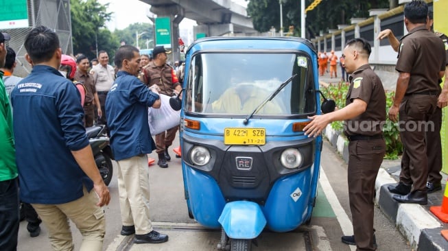 Petugas membagikan paket bantuan bahan pangan di depan Gedung Kejaksaan Agung RI, Jakarta, Senin (1/4/2024). [Suara.com/Alfian Winanto]