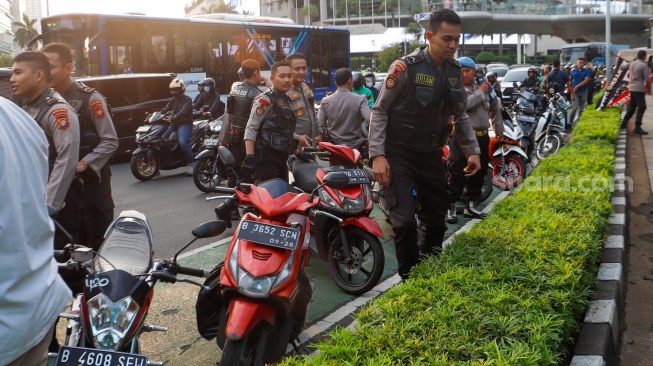 Petugas mengamankan anak-anak saat Razia konvoi kendaraan bermotor di Bundaran HI, Jakarta, Selasa (2/4/2024). [Suara.com/Alfian Winanto]