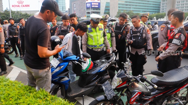 Petugas memeriksa kendaraan saat Razia konvoi kendaraan bermotor di Bundaran HI, Jakarta, Selasa (2/4/2024). [Suara.com/Alfian Winanto]