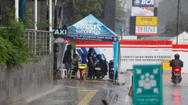 Warga berteduh saat turun hujan di Kawasan Dukuh Atas, Jakarta, Rabu (3/4/2024). [Suara.com/Alfian Winanto]