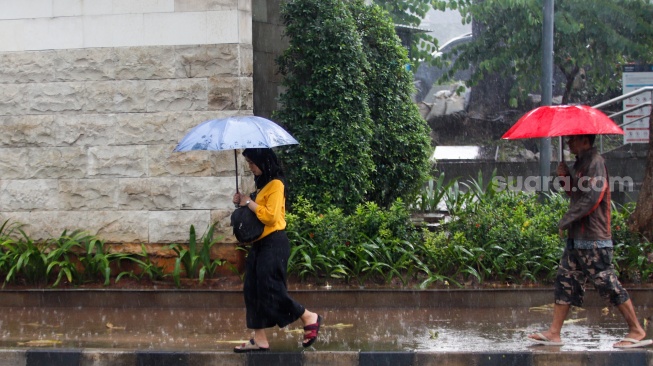 Warga berjalan menggunakan payung saat turun hujan di Kawasan Dukuh Atas, Jakarta, Rabu (3/4/2024). [Suara.com/Alfian Winanto]