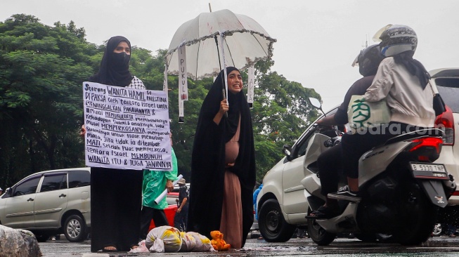 Massa melakukan aksi teaterikal saat menggelar aksi bela Palestina di depan Kedutaan Besar Amerika Serikat, Jakarta, Jumat (5/4//2024). [Suara.com/Alfian Winanto]