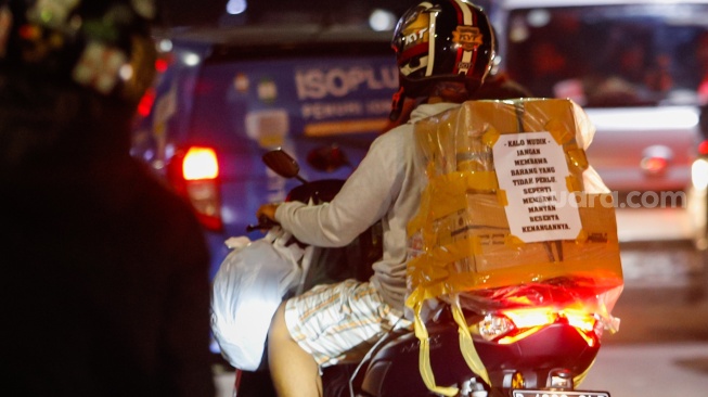 Kertas berisi pesan - pesan terpasang di belakang kendaraan pemudik bersepeda motor yang melintas di Jalan Inspeksi Kalimalang, Jakarta, Sabtu (6/4/2024). [Suara.com/Alfian Winanto]