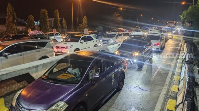 Antrean mobil yang hendak ke Pelabuhan Merak di Tol Tangerang-Merak, Sabtu (6/4/2024) Malam.  [Yandi Sofyan/Suara.com]