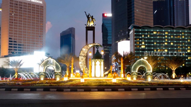 Sejumlah kendaraan melintas di depan dekorasi lebaran di kawasan Bundaran Hotel Indonesia, Jakarta, Senin (8/4/2024). [Suara.com/Alfian Winanto]