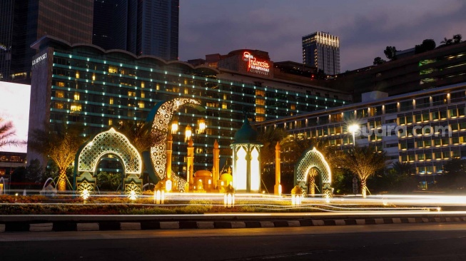 Sejumlah kendaraan melintas di depan dekorasi lebaran di kawasan Bundaran Hotel Indonesia, Jakarta, Senin (8/4/2024). [Suara.com/Alfian Winanto]