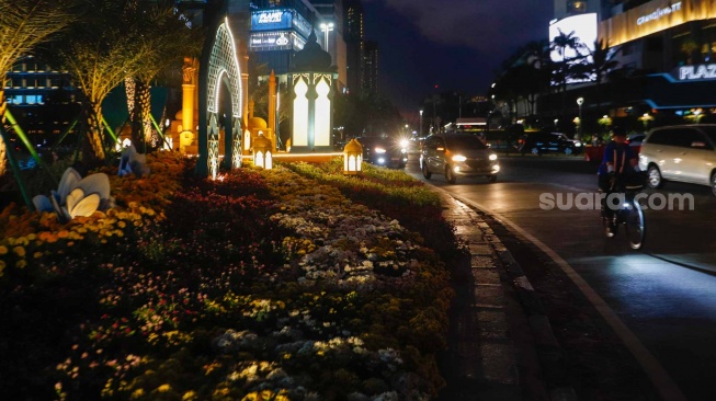 Sejumlah kendaraan melintas di depan dekorasi lebaran di kawasan Bundaran Hotel Indonesia, Jakarta, Senin (8/4/2024). [Suara.com/Alfian Winanto]