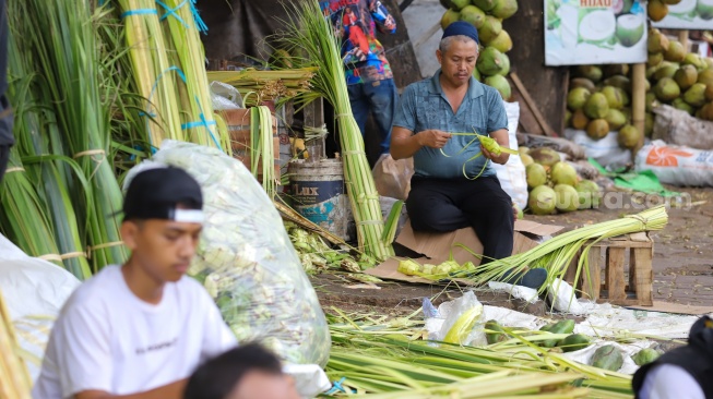 Pedagang menyelesaikan pembuatan kulit ketupat di Pasar Palmerah, Jakarta, Selasa (9/4/2024). [Suara.com/Alfian Winanto]