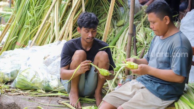 Pedagang menyelesaikan pembuatan kulit ketupat di Pasar Palmerah, Jakarta, Selasa (9/4/2024). [Suara.com/Alfian Winanto]