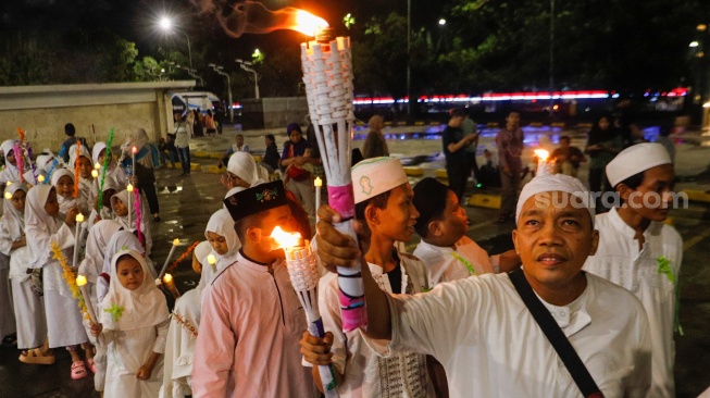 Sejumlah warga melakukan pawai obor malam takbiran di kawasan Masjid Istiqlal, Jakarta, Selasa (9/4/2024). [Suara.com/Alfian Winanto]