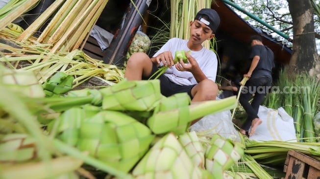 Pedagang menyelesaikan pembuatan kulit ketupat di Pasar Palmerah, Jakarta, Selasa (9/4/2024). [Suara.com/Alfian Winanto]