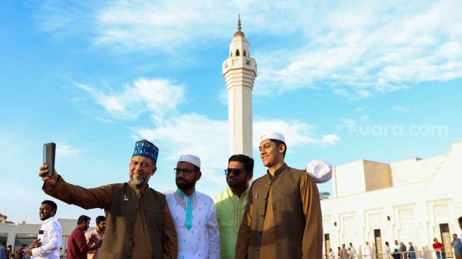 Warga Muslim berfoto selfie setelah salat Idul Fitri, yang menandai akhir bulan suci Ramadhan, di masjid Ali Bin Ali di Doha, Qatar, Rabu (10/4/2024). [KARIM JAAFAR / AFP]