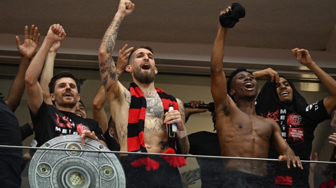 Para pemain Bayer Leverkusen berselebrasi dengan replika trofi Bundesliga setelah pertandingan sepak bola Bundesliga antara Bayer Leverkusen dan Werder Bremen di Leverkusen, Jerman barat, Minggu (14/4/2024). [INA FASSBENDER / AFP]