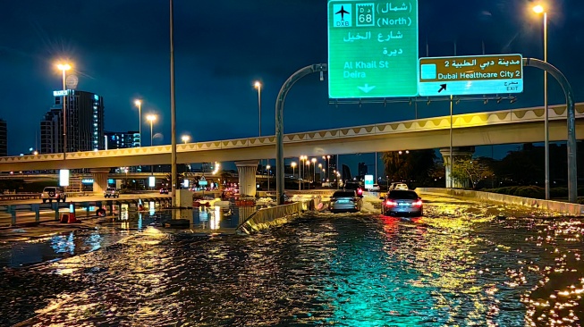 Pengendara berkendara di sepanjang jalan yang banjir setelah hujan lebat di Dubai, Uni Emirat Arab, Rabu (17/4/2024).  [Giuseppe CACACE / AFP]