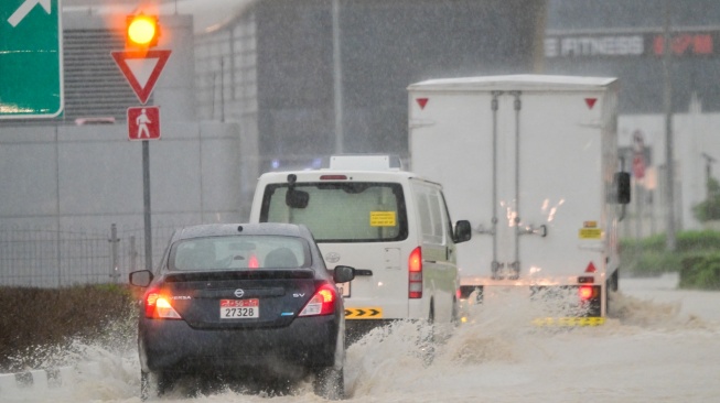 Kendaraan melaju di jalan yang banjir saat hujan deras di Dubai, Uni Emirat Arab, Selasa (16/4/2024).  [Giuseppe CACACE / AFP]