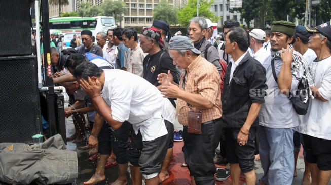 Massa mengambil air wudhu untuk salat jumat berjamaah saat aksi tolak pemilu curang di Patung Kuda, Jakarta, Jumat (19/4/2024). [Suara.com/Alfian Winanto]
