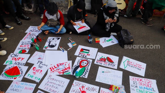 Sejumlah massa membuat tulisan dan gambar saat menggelar aksi solidaritas untuk Palestina di depan Kantor Kedutaan Besar Amerika Serikat, Jakarta, Jumat (19/4/2024). [Suara.com/Alfian Winanto]