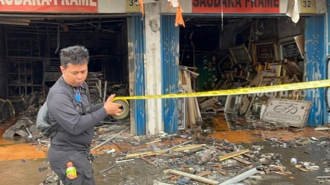 Penampakan aparat gabungan saat memasang police line di Ruko Saudara Frame dan Gallery, di Jalan Mampang Prapatan Raya, Jakarta Selatan usai ludes terbakar dan menewaskan tujuh korban jiwa. (Suara.com/M Yasir)