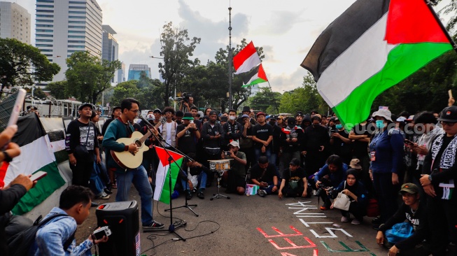 Sejumlah musisi tampil saat menggelar aksi solidaritas untuk Palestina di depan Kantor Kedutaan Besar Amerika Serikat, Jakarta, Jumat (19/4/2024). [Suara.com/Alfian Winanto]