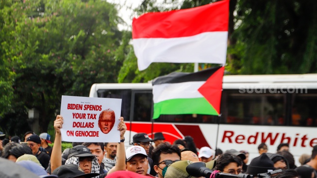 Sejumlah massa mengangkat poster dan bendera saat menggelar aksi solidaritas untuk Palestina di depan Kantor Kedutaan Besar Amerika Serikat, Jakarta, Jumat (19/4/2024). [Suara.com/Alfian Winanto]