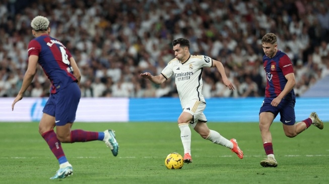 Penyerang Real Madrid asal Spanyol, Lucas Vazquez (tengah) menggiring bola selama pertandingan pekan ke-32 Liga Spanyol antara Real Madrid vs Barcelona di stadion Santiago Bernabeu di Madrid pada 21 April, 2024.Thomas COEX / AFP.