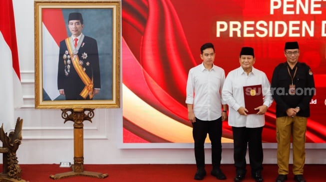 Presiden dan Wakil Presiden Terpilih Periode 2024-2029, Prabowo Subianto (tengah) dan Gibran Rakabuming Raka (kiri) bersama Ketua KPU Hasyim Asy'ari (kanan) saat menerima surat penetapan dalam Rapat Pleno Terbuka Penetapan Pasangan Capres-Cawapres Terpilih di Gedung KPU, Jakarta, Rabu (24/4/2024). [Suara.com/Alfian Winanto]