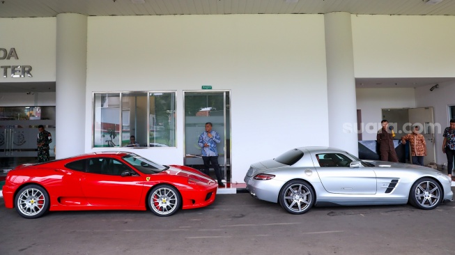 Penampakan dua mobil mewah berjenis Ferrari (merah) dan satu Mercedes Benz (putih) milik suami Sandra Dewi, Harvey Moeis, yang disita jaksa penyidik dan ditempatkan di depan Gedung Kartika Kejaksaan Agung, Jakarta, Jumat (26/4/2024). [Suara.com/Alfian Winanto]