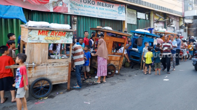 Warga mengantre mie ayam gratis di wilayah Menteng Wadas Timur, Jakarta, Selasa (30/4/2024). [Suara.com/Alfian Winanto]