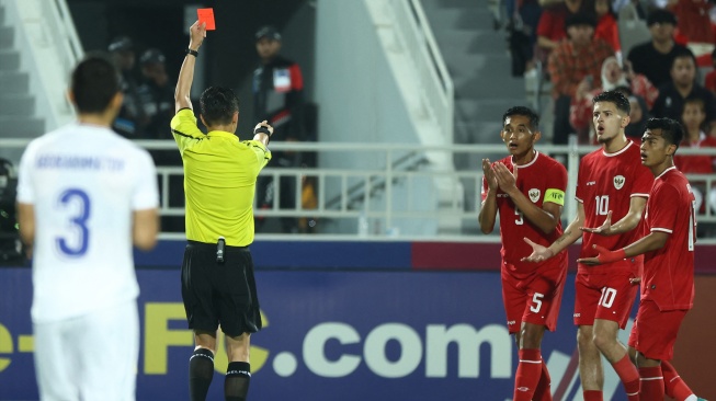 Wasit Shen Yinhao memberikan kartu merah kepada bek Indonesia Rizky Ridho saat pertandingan semifinal Piala Asia U23 2024 antara Indonesia melawan Uzbekistan di Stadion Abdullah bin Khalifa, Doha, Qatar, Senin (29/4/2024). [Karim JAAFAR / AFP]