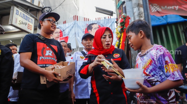 Relawan Jokowi membagikan susu kepada anak-anak di wilayah Menteng Wadas Timur, Jakarta, Selasa (30/4/2024). [Suara.com/Alfian Winanto]