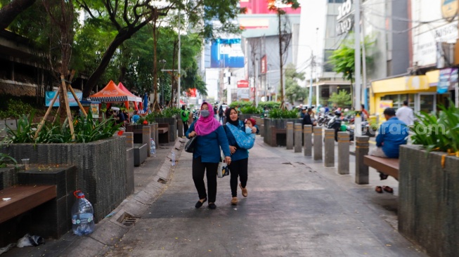 Warga berjalan melewati kawasan Transport Hub Dukuh Atas, Jakarta, Selasa (30/4/2024). [Suara.com/Alfian Winanto]