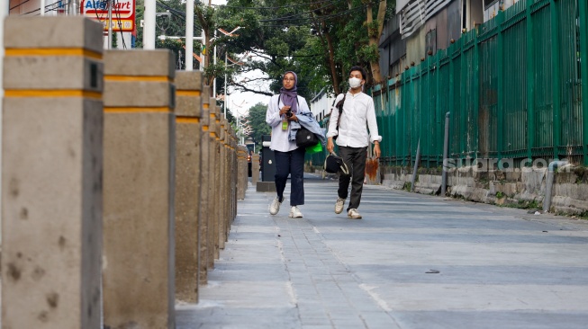 Warga berjalan melewati kawasan Transport Hub Dukuh Atas, Jakarta, Selasa (30/4/2024). [Suara.com/Alfian Winanto]