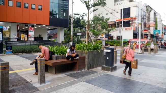 Warga berjalan melewati kawasan Transport Hub Dukuh Atas, Jakarta, Selasa (30/4/2024). [Suara.com/Alfian Winanto]