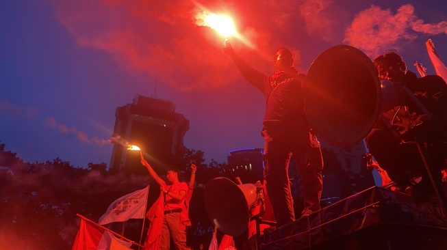 Massa Aksi Hari Buruh di Kawasan Patung Kuda Jakarta menyalakan flare sebelum membubarkan diri, Rabu (1/5/2024). [Suara.com/Faqih]