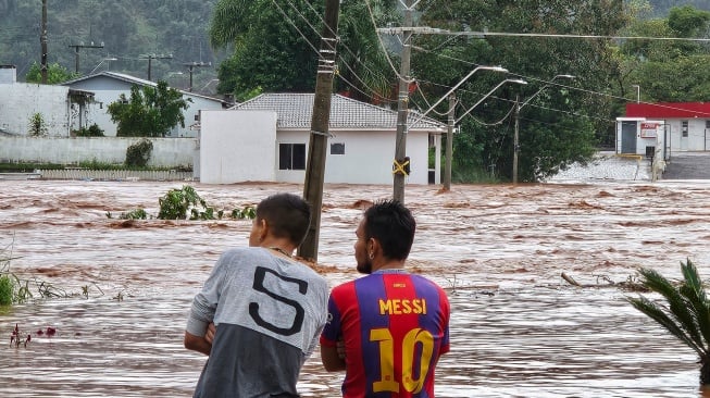 Warga mengamati jalan yang banjir setelah hujan lebat di kota Encantado, Rio Grande do Sul, Brasil, Rabu (1/5/2024). [Gustavo Ghisleni / AFP]