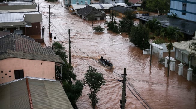 Relawan menggunakan perahu nelayan untuk menyelamatkan warga yang terjebak di dalam rumah mereka di pusat kota Sao Sebastiao do Cai, Rio Grande do Sul, Brasil, Kamis (2/5/2024). [Anselmo Cunha / AFP]