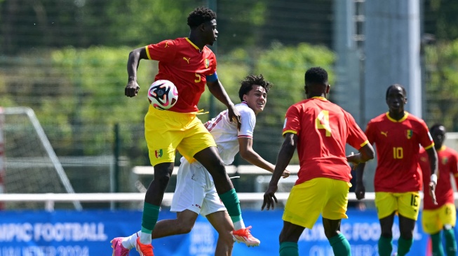 Bek Guinea Saidou Sow (Kiri) berebut bola dengan penyerang Indonesia Rafael Struick selama pertandingan play-off pra-Olimpiade antara Indonesia dan Guinea di Clairefontaine-en-Yvelines, selatan Paris, Prancis, Kamis (9/5/2024). [MIGUEL MEDINA / AFP]