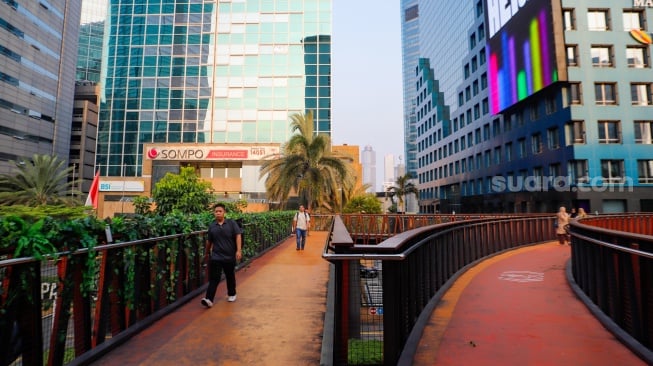 Warga mengunjungi Jembatan Penyebrangan Orang (JPO) Pinisi di Jalan Jenderal Sudirman, Jakarta, Jumat (10/5/2024). [Suara.com/Alfian Winanto]