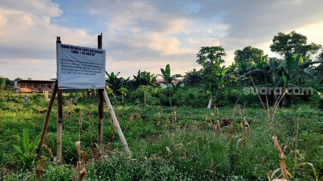 Warga memasang papan pengumuman sebagai pemilik lahan di lokasi pembangunan stadion Sudiang, Kota Makassar [SuaraSulsel.id/ Lorensia Clara Tambing]