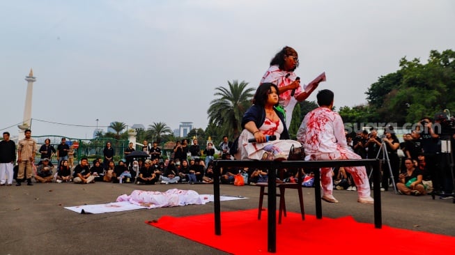 Sejumlah mahasiswa dari Sekolah Tinggi Filsafat Driyarkara menampilkan teaterikal pada Aksi Kamisan ke-815 di sebrang Istana Negara, Jakarta, Kamis (16/5/2024). [Suara.com/Alfian Winanto]