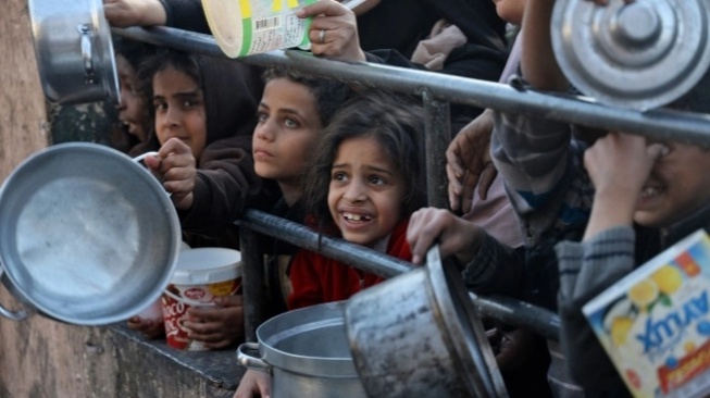 Pengungsi Palestina mengumpulkan makanan yang disumbangkan oleh sebuah badan amal untuk berbuka puasa di Rafah, Jalur Gaza Selatan, Senin (11/3/2024). [AFP]